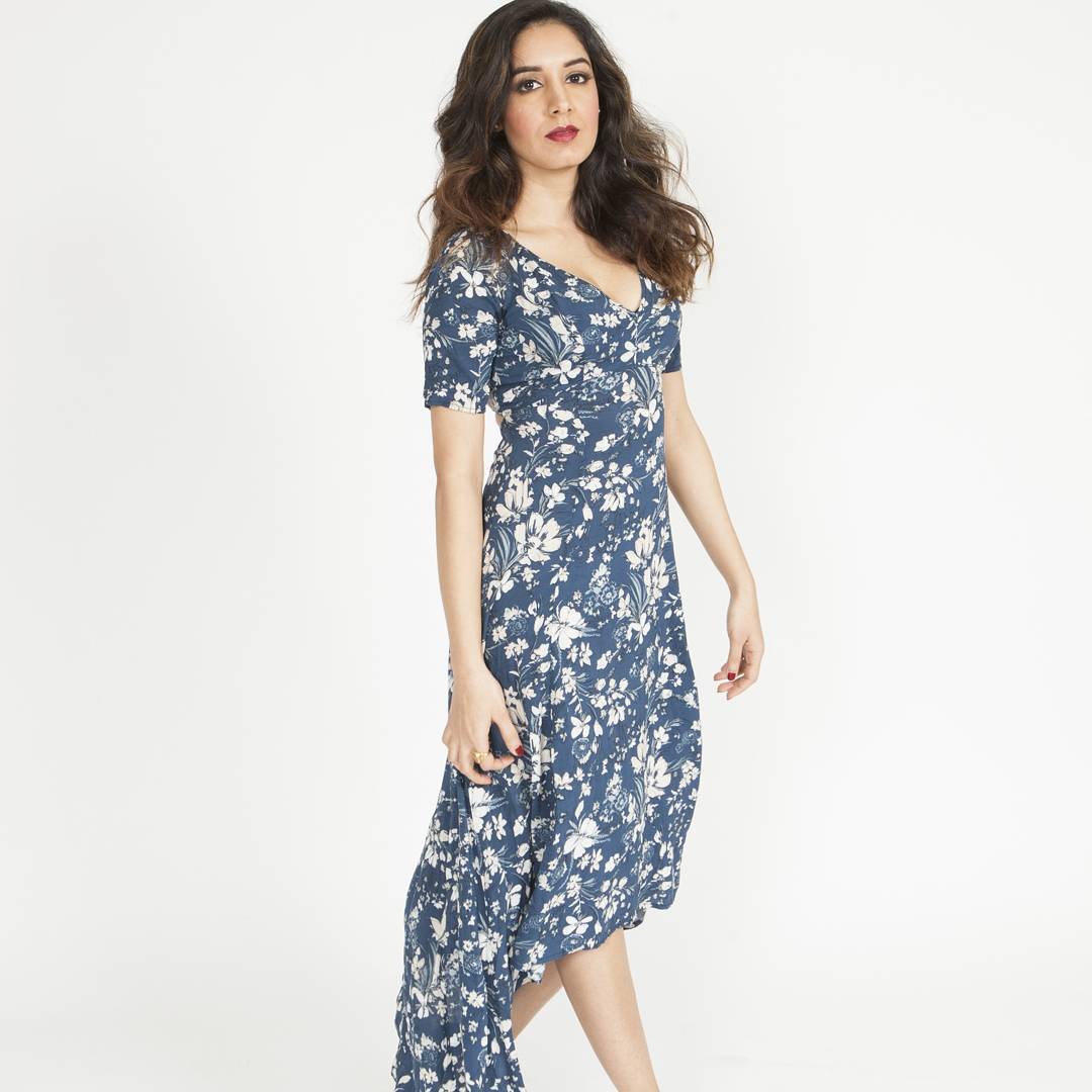 Full-length editorial fashion portrait with soft waves and camera-ready glam in a blue floral dress