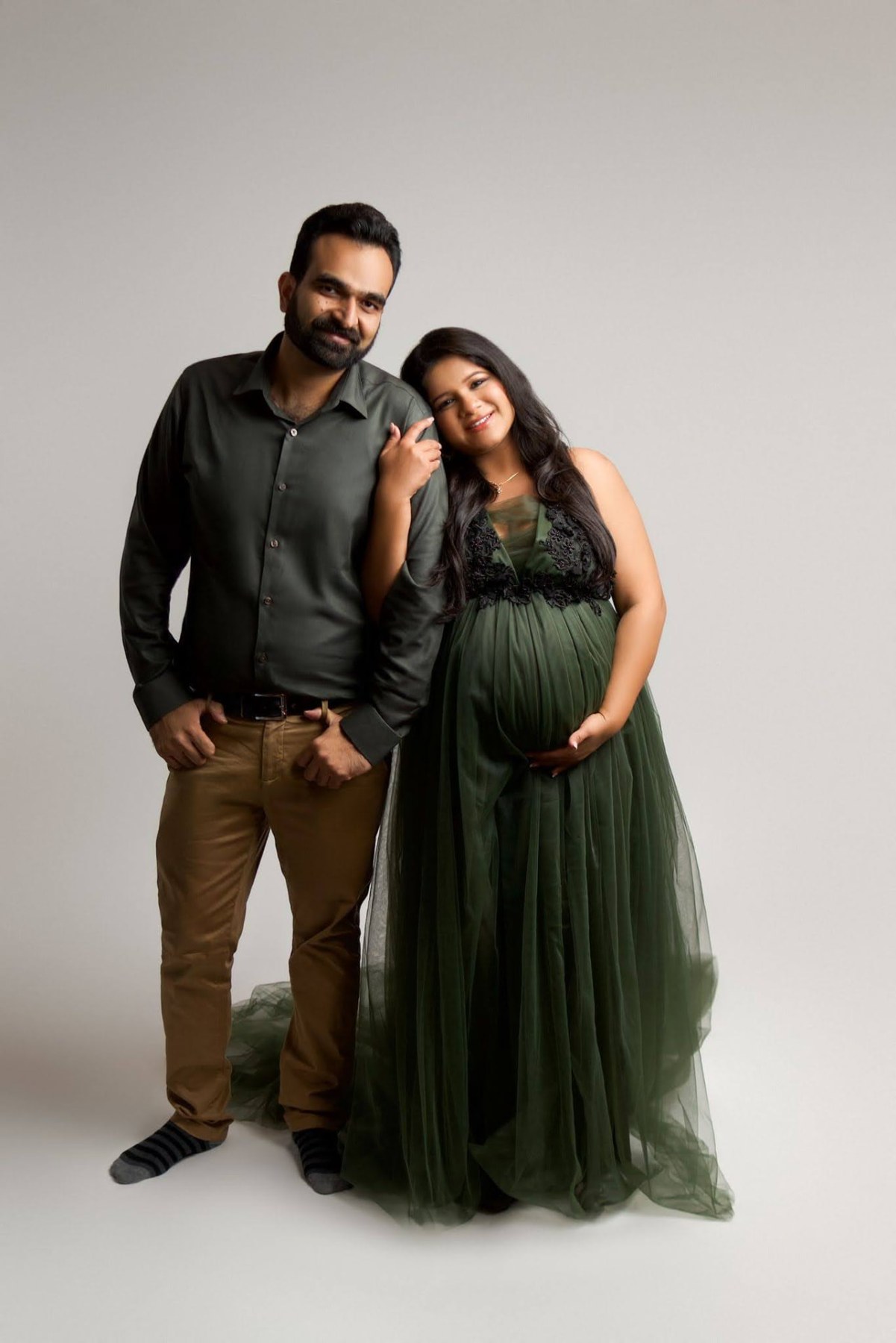 Maternity couple portrait with glowing skin, defined eyes and a soft berry lip in an emerald gown