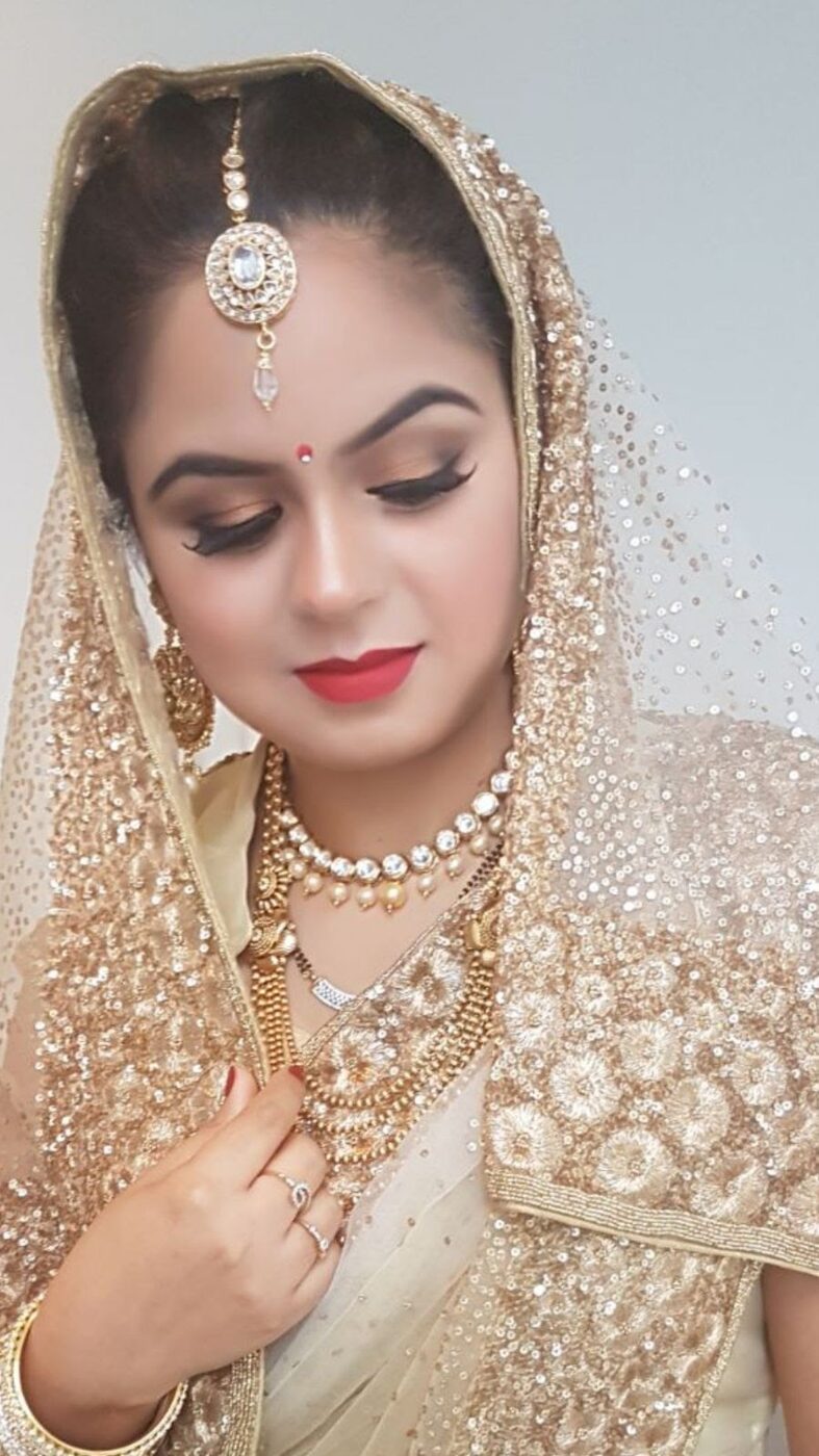 Bridal makeup with soft smoky eye, winged liner and a deep red lip, styled with a gold dupatta