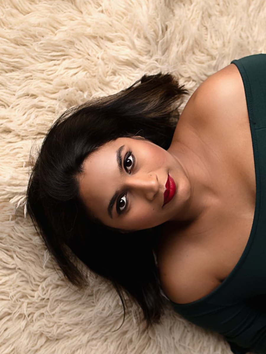 Close-up maternity portrait with sculpted brows, soft smoky eyes and a classic red lip in an emerald gown