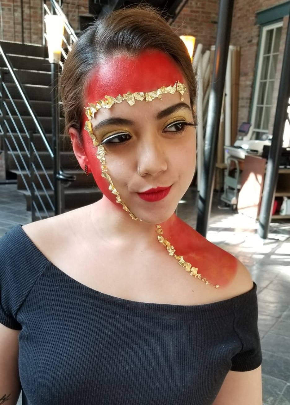 Editorial makeup look with red pigment, gold leaf detailing and a bold red lip