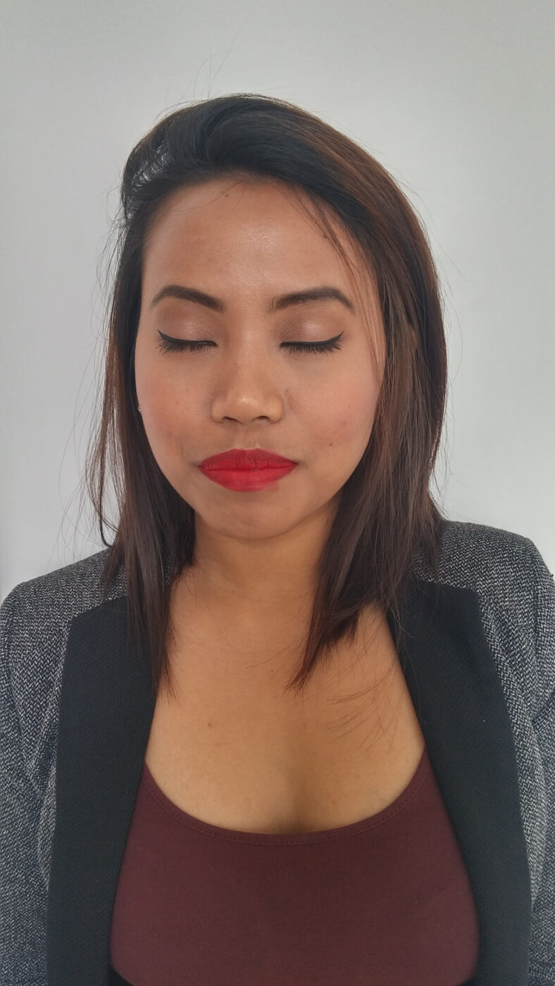 Close-up of headshot makeup showing neutral shadow, sharp liner and a matte red lip