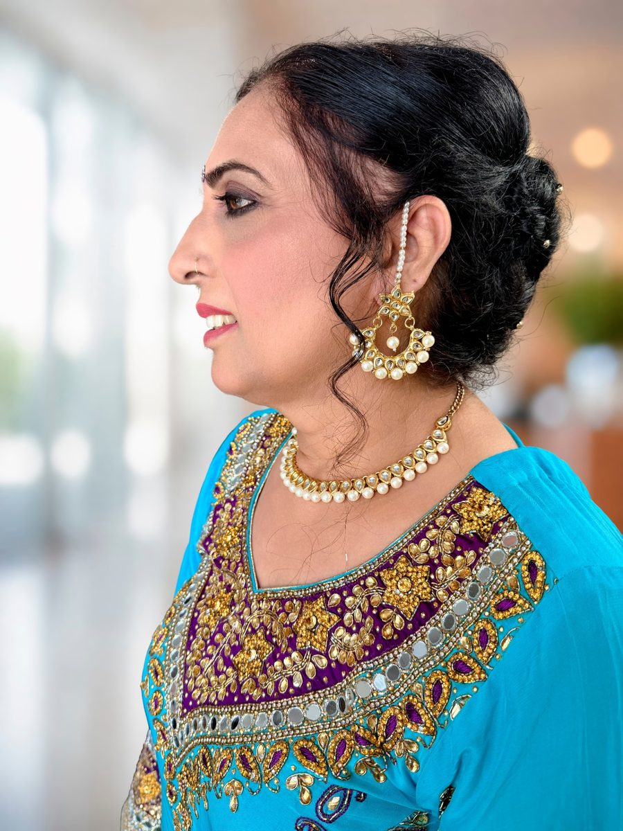 Side profile of mother-of-the-groom makeup with a bronze smoky eye, winged liner and a pearl ear chain in an elegant updo