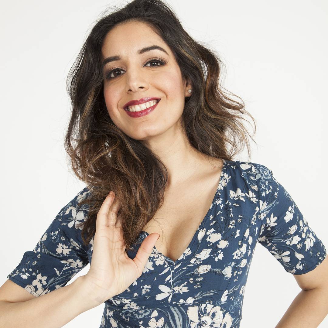 Smiling fashion portrait with soft bronze eyes, glowing skin and a berry lip in a blue floral dress