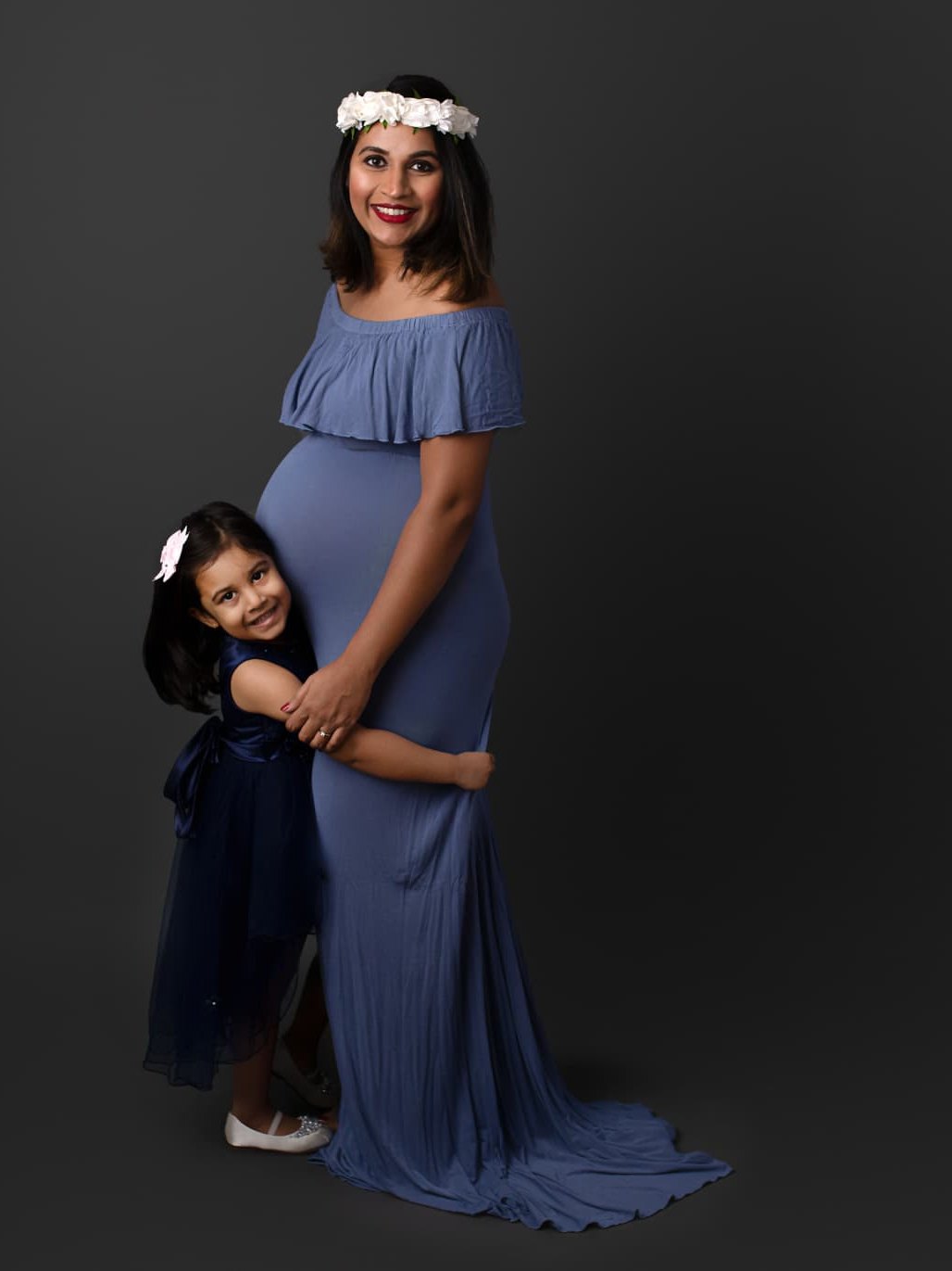 Mother and daughter maternity studio portrait with glowing camera-ready makeup and a red lip