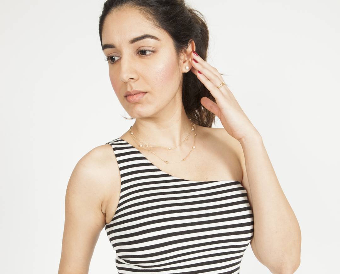 Three-quarter editorial studio portrait with dewy skin, subtle bronzing and a natural lip