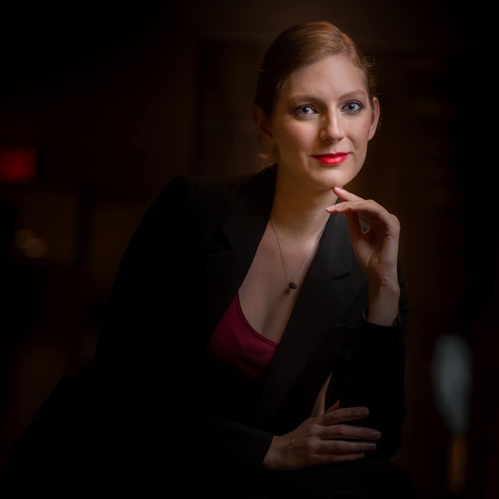 Moody studio headshot with sculpted features, luminous skin and a classic red lip