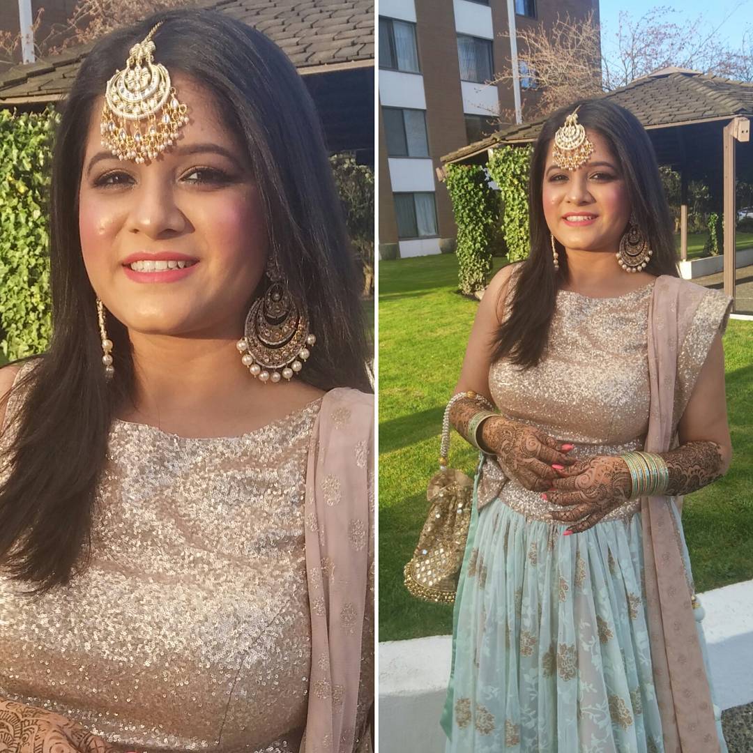 Outdoor bridal portrait with soft glam eyes, glowing skin and a rose lip, styled with a maang tikka and statement earrings