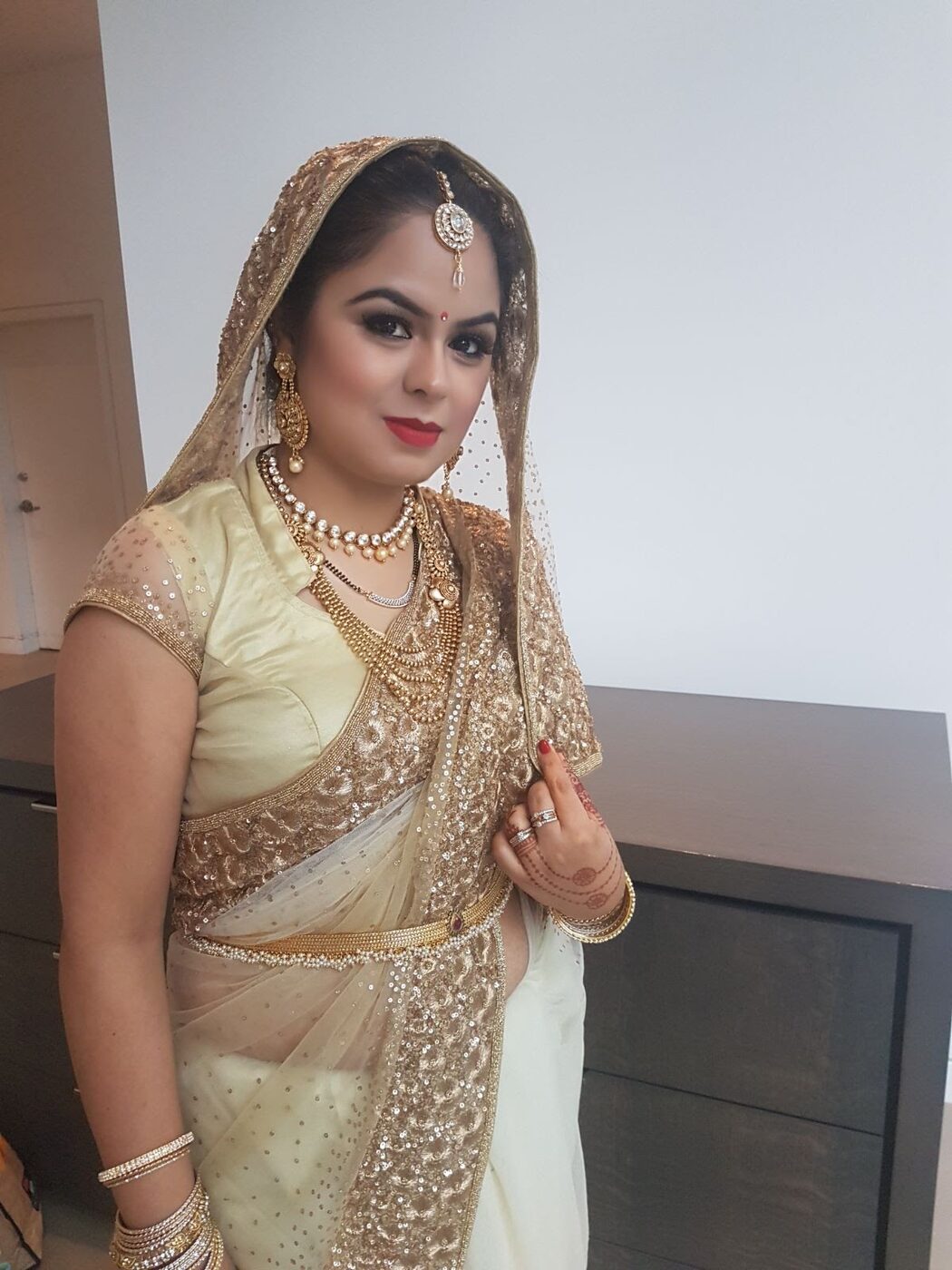 Bridal makeup with defined brows, smoky eyes and a bold lip under a gold veil